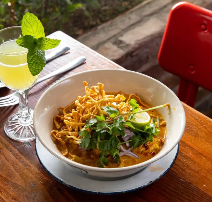 Curry noodles topped with crispy noodles, fresh herbs and lime at Glai Baan